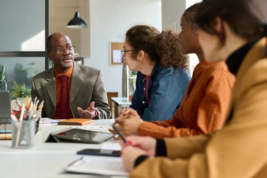 A group of young professionals asking for career advice from a senior-level employee